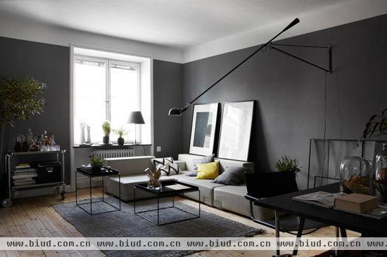 灰色的墙壁与白色的天花使得空间在视觉上有分层的感觉，再加上独特的长支架台灯和呈长方体形状的两张桌子，客厅的立体感十分强烈。