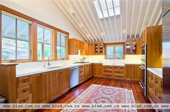 该长方形厨房较为开阔，安置了多个储物柜，包括壁橱，都是木质的，与房屋整体的装修相统一，也具有很好的收纳作用。