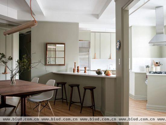 质朴的木餐桌与时尚的餐椅相搭配，再加上工业风的吊灯，餐厅空间简约平实。与传统的独立吧台不一样，隔断餐厅与厨房的吧台与墙壁和门框相连，使二厅空间相对独立。