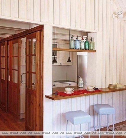 木质的格门划出一个清新感十足的厨房空间。厨柜整体采用了现代感的简约设计，线条简洁，造型规整。干净的配色能够与其他空间的环境相协调，全封闭式的储物空间保证了厨房的整体性和利落感。