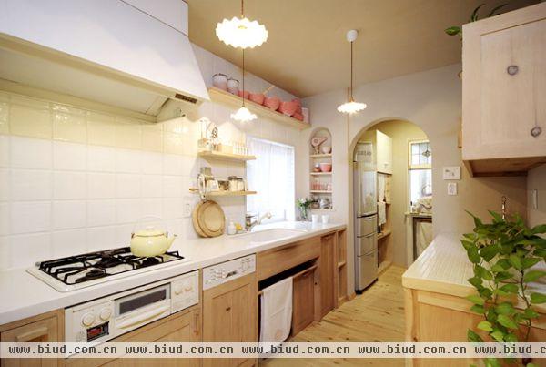  家庭装修样板房：狭长的厨房空间是常见的户型，在这里可以设计一字型操作台，木质的橱柜搭配白色台面以及白色墙砖，看起来简单朴素，但却亦是样样俱全。 
