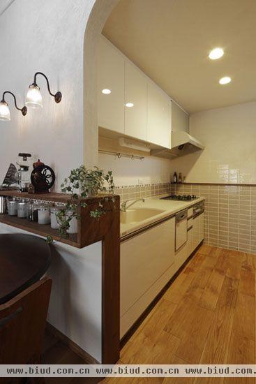 厨房区域，白色和木色为主，清爽整洁。木色的地板，清晰可见的木质纹理，年轮的样式，仿佛记录着生活的点点滴滴，简约时尚。白色的整体橱柜，尽显干净整洁之感。灰色、白色马赛克拼凑的墙面，不仅可以避免油烟弄脏墙壁，而且干净的色彩让整个空间都变的格外规整大方，做饭的时候也不失品位。