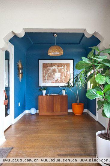 Lisa的房子在进门处拥有一个宽敞的大玄关，蓝色的前面搭配上橙色的花盆以及一旁木制的地柜，用鲜明撞色带来强烈的视觉效果来诠释加州的阳光、蓝天展现出来的好风景。习惯性地沿用经典的美式白边门框设计，也让Lisa崇尚的这种经典融入到家居的细节中去。