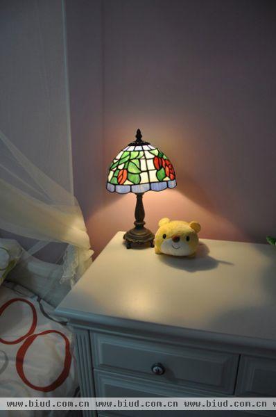 床头柜上面是一盏地中海的台灯，彩色玻璃