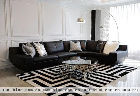 沙发上的抱枕是小重点之一，黑白灰银相邻的四种颜色放置在真皮沙发上，缓解黑白过于强烈的视觉冲击。沙发后的倒U型灯饰是小重点之二，淡黄色的灯光和柔和的曲线线条，使室内线条刚柔平衡。