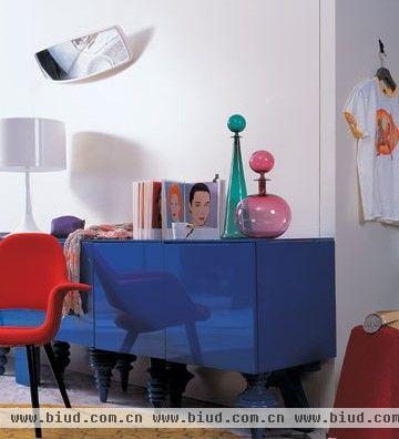 强烈的色彩对比中，白色的适当点缀平衡了空间的色彩关系，而柔和的面料让硬朗的房间多了一份舒适感。超大比例的装饰镜、蓝色漆光质感的边柜，成为整个房间的亮点，让家透出一份感性和活力。