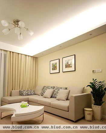 在明亮的灯光下，米色的空间显得更加清新简约，搭配一些绿色植物，让英伦风格更有韵味。沙发背景墙只用两幅简单的挂画装饰，突出墙面的色彩，与整体色彩的搭配