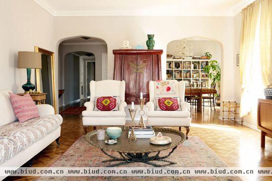 复古的地毯划出了客厅区域，原始风的托盘状桌子提升了客厅的质感，对称的白色沙发和圆角矩形门平衡了布局的同时使空间质感更加柔和。