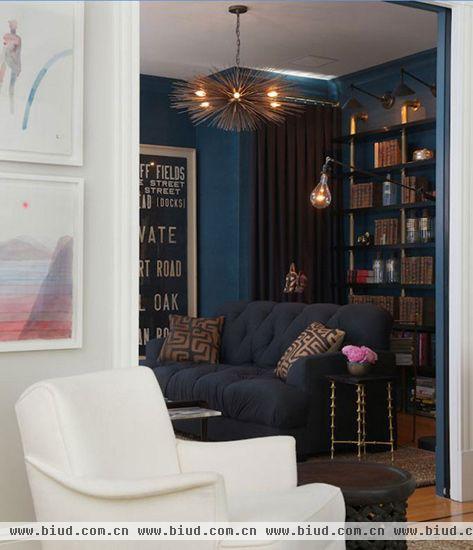蓝色背景的办公房使其很容易与白色背景的客厅区分开来，冷色调的办公房让人的情绪容易平静下来，金属质感的吊灯、小桌子和书架教人沉着冷静。