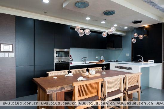 把建商附的L型厨房厨具换成一字型，让一整排厨具沿着墙面发挥最完整的收纳与动线机能，后方用中岛吧台连结餐桌，规划出15平米的烹煮与用餐区域。
