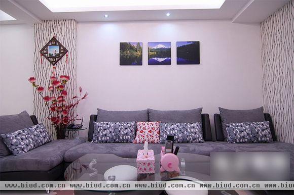 走进客厅，灰色的L型布艺设计显得大气又舒适。沙发后面的三幅图画和茶几上的花，让单调的背景墙增色不少。显得简洁又不乏生气。