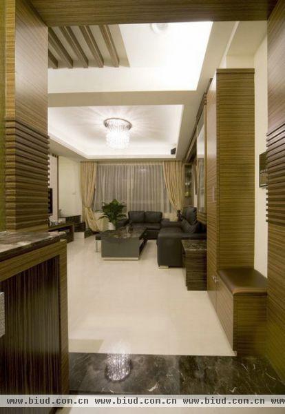 其中以木作以深浅颜色来表现空间的优雅氛围。其中玄关进入客厅区域相同的门拱木做造型作为设计元素，利落而和谐的区分彼此的地域关系。