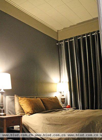 寝室是一个非常私密的空间，用深灰色的墙面和窗帘布保持寝室的神秘感。床上用了墨绿色的四件套，体现男子汉的硬朗沉着。夏天这个炎热的季节，选用床上用品的时候优先选择棉布材质，清爽、吸汗、耐清洗。