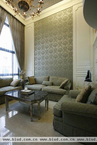 落地窗以灰绿的窗帘及窗纱围塑出宫庭般气势，与壁纸及沙发柔和的色调合而为一，协调的美感建构温馨放松的居家氛围。