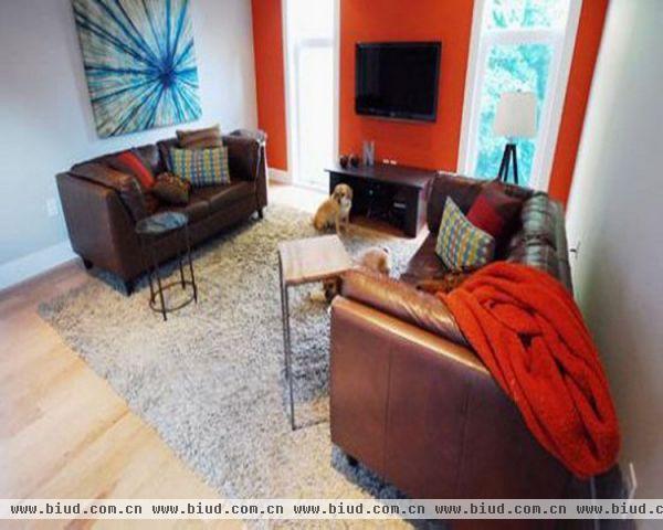 两面是素白色墙壁的客厅里，有一面采用了艳丽的橙红色。给单调的客厅带来了巨大的色彩冲击。