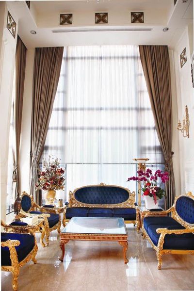 设计师将客厅高度设计至6.2米，挑高的设计凸显宽敞豪气，精选的宝蓝色系镶嵌金箔雕花收边的仿古沙发，将法式古典风格展露无遗