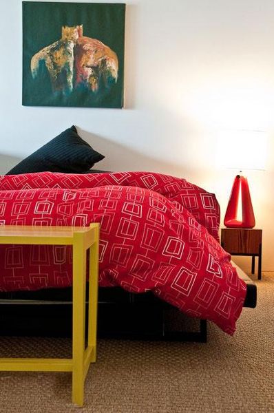 白色的卧室没有多余的累饰，红色的床品保持整个家的色彩统一。 
