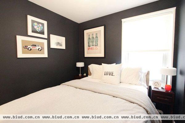 依然是黑白搭配的卧室，整个墙面是黑色的，另外贴上一些挂画作为装饰品。