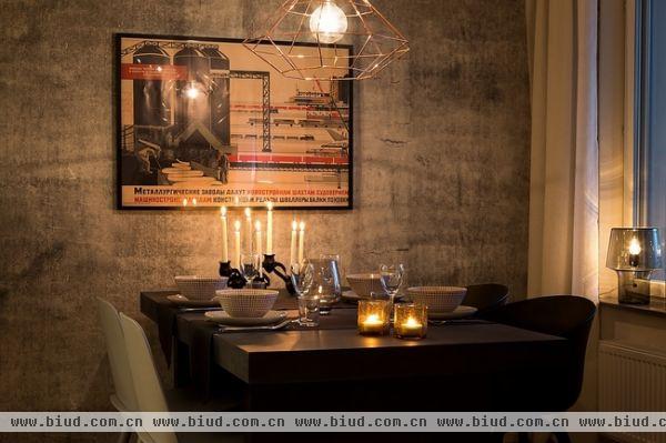 整个空间都是工业化元素，如餐桌上的复古挂画，黑灰色的墙面，工业吊灯。