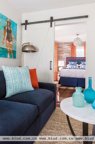 客厅布置加入多元化因素在里面，如藏青色的沙发配上淡蓝色的抱枕，圆形小桌面代替茶几。