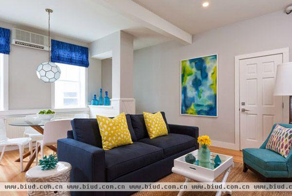 客厅布置加入多元化因素在里面，如藏青色的沙发配上淡蓝色的抱枕，圆形小桌面代替茶几。