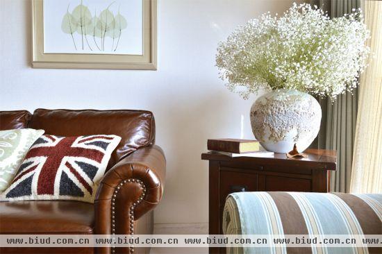 在空间的设计上，小饰品是能起到极大作用的，复古的茶几上摆着插好的雪柳、背景墙上裱了一幅简单的画、沙发上各式图案的小抱枕，这些小饰品放在一起，为客厅增色不少。