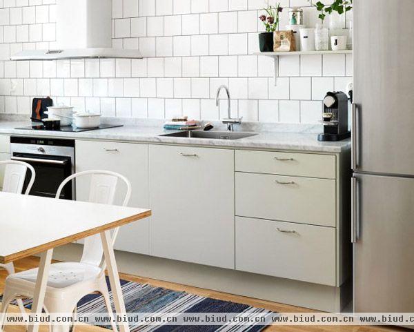 橱柜门使用软灰绿色，简约的白色瓷砖和美丽的大理石台面使厨房温馨，并且非常实用。空间当中，一条长凳上，也以灰绿色装饰，一对Tolix白色椅子创造出一处舒适温馨的早餐空间。瓷砖，家具和地毯的美丽复古情调，使空间显得更加惬意舒适。