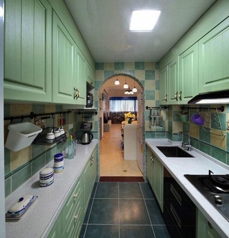 厨房里采用的厨具都是绿色的，从厨房可以看到客厅，空间是很宽敞的，绿色的厨具加上白色的灶台显得很清新，厨房空间宽敞明亮，橱柜很多放东西也很方便。