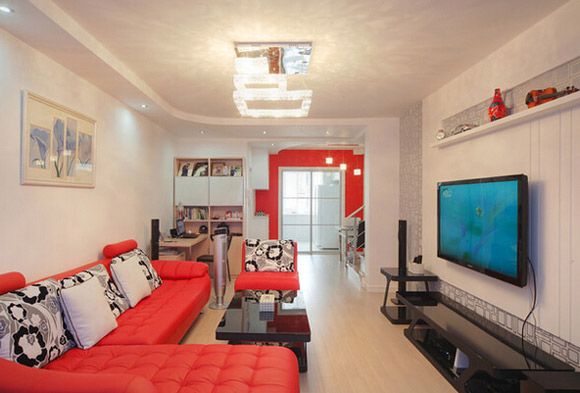 夺目的红色沙发放在客厅里很温馨也很喜庆，沙发是L型的摆设方式，实用又大方。黑色的茶几与电视下面的地柜是一套的，整个客厅选择的家居都很协调。