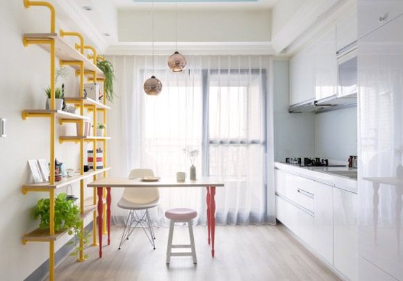 以白色为基调的厨房里还设有一张餐桌，这里虽有不少鲜艳的色彩，但饱和度却有控制，整体上给人清新的感觉，白色的橱柜使厨房更明亮。