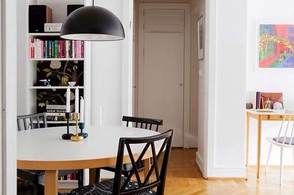 原型的实木餐桌白色台面，配上黑色的餐椅，正上方悬挂着黑色半圆吊灯。