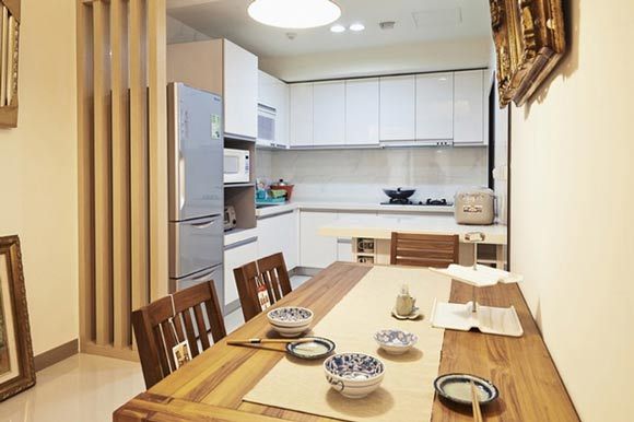 这里餐厅和厨房的位置是相邻的，餐厅依然选用实木的餐桌椅与整体风格相协调，现在很多家庭都将厨房和餐厅进行一体化的设计，不过这里有一点要提醒大家的就是，开放式的厨房设计油烟会比较大，如果想设计成这样的餐厨空间可以考虑在两者的中间设计一个玻璃的隔断或是屏风。