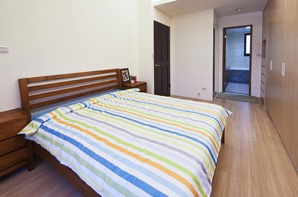简约的卧室，也是根据居住着的需求，深思熟虑静心设计出来的，床的对面是一排整体式实木衣橱，自然纹路的实木地板，偏深色系的床，卧室里虽没有过多的装饰，住着却很舒适。