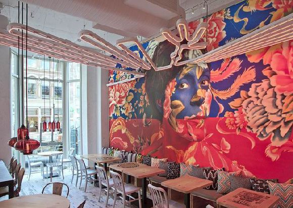 整个餐厅设计非常的丰富，入口处墙面的装饰画是一位秘鲁艺术家的作品“两个世界”，顶部的霓虹灯也采用了秘鲁南部风格的线条。继续走进，不仅有竹子围绕的餐桌还有日式榻榻米。而整体的正红色则拥有浓厚的中国风，混搭的风格，充满了魔幻的色彩。