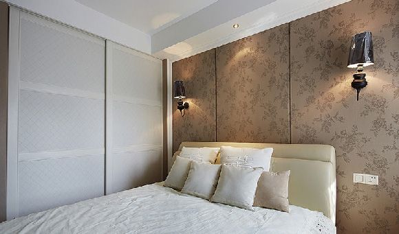 卧室选用了浅色床具和床品，与背景墙的咖色花纹壁纸搭配起来显得简洁又温馨。