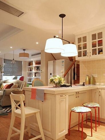 这间小复式的公寓中，一楼楼梯旁便是这间公寓的厨房所在，白色系橱柜巧妙的让这间厨房从视觉上得到空间扩容的效果，而开放式的格局更是让这一空间看起来宽敞实用，以宽宽的岛台来作为吧台的设计，在日常生活中也是相当实用的一种设计。
