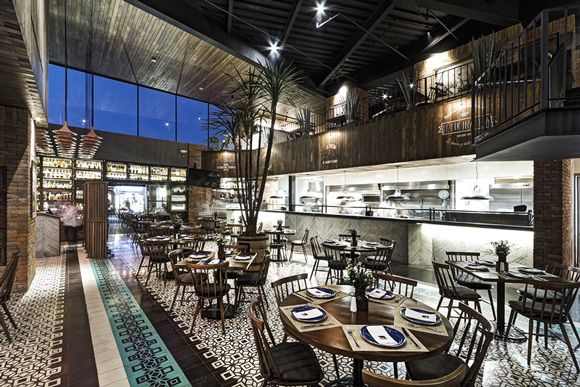 整间餐厅的装饰原生态十足，将复古和典雅的设计风格进行到底。黑白格子相间的地板增添强烈的视觉冲击感，呈现出一番精致低调。以木质材料为主打造的餐厅，让整个空间更加亲近自然，点缀的绿色植物更加呼应整个氛围。铁质的楼梯、用普通砖块砌成的柱子为整间餐厅又添加了些许工业风。