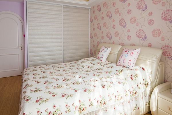Kitty家的壁纸也是一大特色。客厅和卧室的壁纸选择的都是鲜花的图样，客厅是木槿花，清秀温馨的花纹搭配上粉色的窗帘，使得原本大空间直筒型的客厅更加田园自然。主卧选择的是大花葱的图样，床单布艺也是碎花纹样。