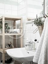 浴室很简约，延续了柔和色调以及实用家具的主题。灰色和黑色的颜色作为背景，简单的装饰。木架子和浴室配件能够很好地将小空间转换成理想的功能空间。