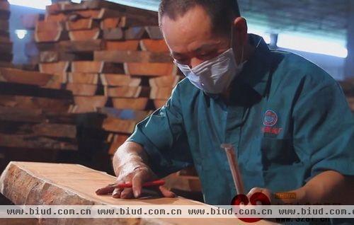 水雨轩功夫茶具工厂车间的工人根据木板的特点，斟酌如何进行开料