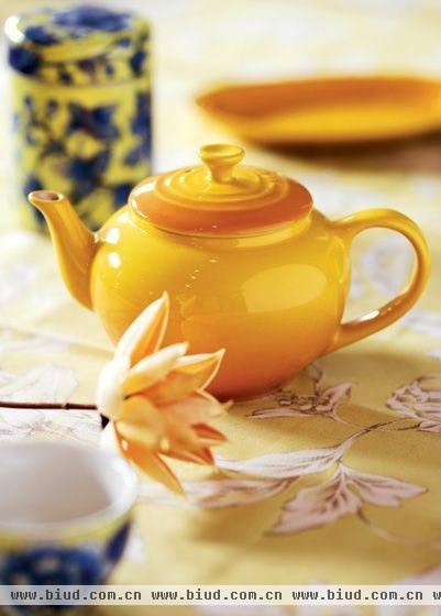 黄色的陶瓷茶壶搭配黄地白花桌布