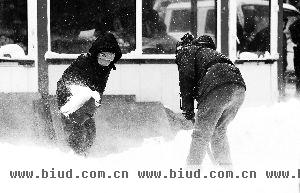 11月18日，哈尔滨发布暴雪红色预警，全城动员清冰雪。一对母子在自家商铺门前清扫积雪。 新华社发
