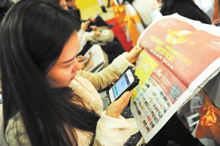 一位消费者正用手机扫描长沙晚报刊登的“福满星城”二维码