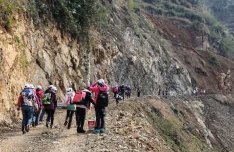 崎岖的山路没法通车，志愿者们途步搬物资上山