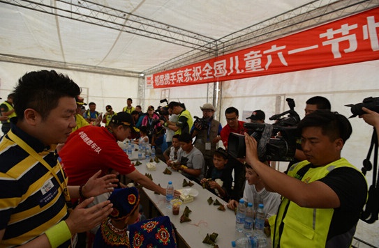  孩子们开始吃粽子啦，CCTV5主持人李晨明及其他媒体正在做现场录制拍摄