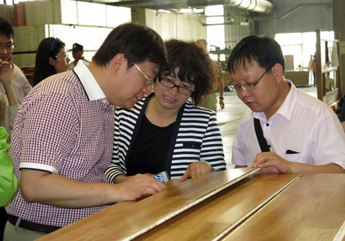 圣象集团市场部总经理王晓宇在给记者们介绍三层实木地板的结构优势