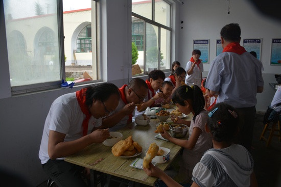 志愿者与小朋友在新的餐桌上共同吃午餐