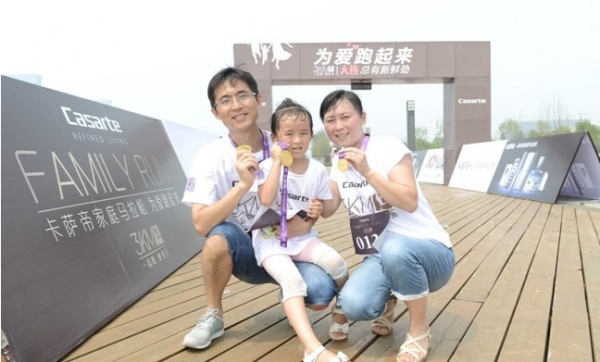 图片三：在大连海边木栈道上，父母带着女儿一家三口共同完成3KM，收获爱的奖牌
