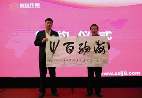 中国建筑装饰协会秘书长张仁先生（右）向盛世乐居董事长郑炜先生（左）赠送亲笔题词：“海纳百川”