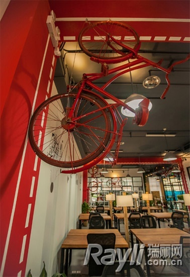 废旧自行车被刷上红颜色的油漆，按照不同姿态悬挂在办公室的屋顶